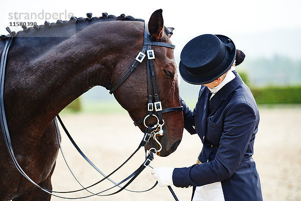 Reiterin beim Streicheln von Dressurpferden in der Reitarena