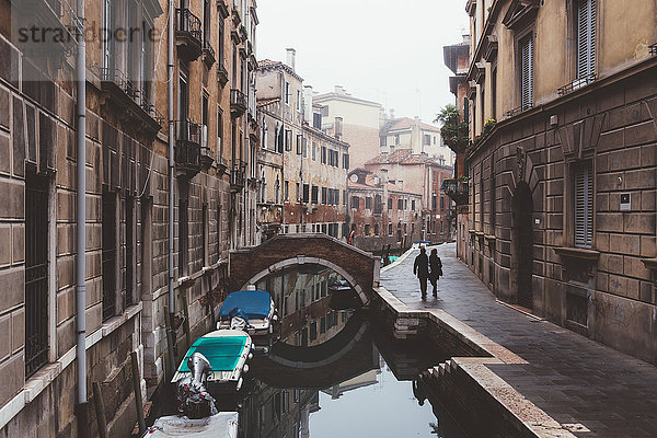 Rückansicht eines Paares  das am Ufer des Kanals spazieren geht  Venedig  Italien