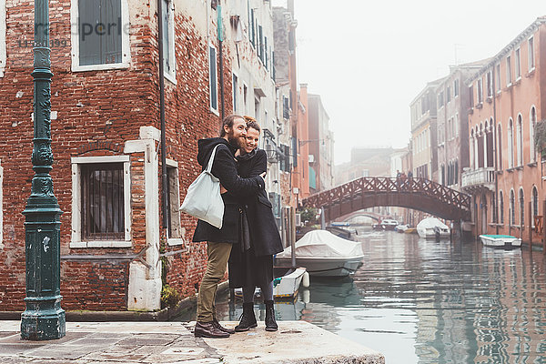Ehepaar umarmt sich am Ufer des nebligen Kanals  Venedig  Italien