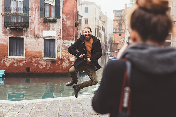 Frau fotografiert Mann beim Kanalspringen  Venedig  Italien