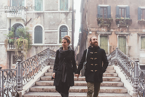 Paar  das sich an den Händen hält und die Treppe hinuntergeht  Venedig  Italien