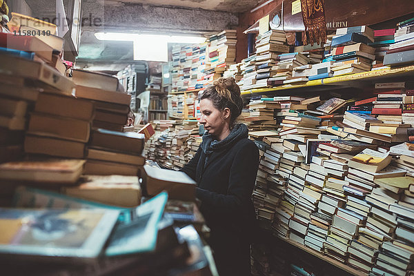 Junge Frau stöbert in gestapeltem Buchladen  Venedig  Italien