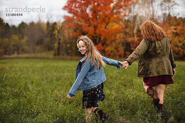 Mutter und Tochter halten sich beim Spaziergang auf einer Wiese an den Händen  Lakefield  Ontario  Kanada