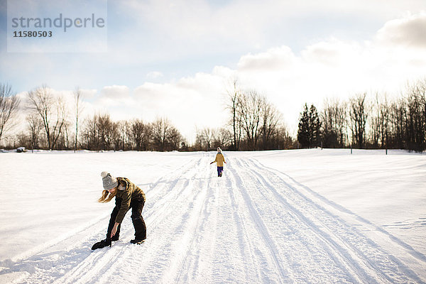 Mädchen hebt Fäustling auf schneebedecktem Weg auf  Lakefield  Ontario  Kanada