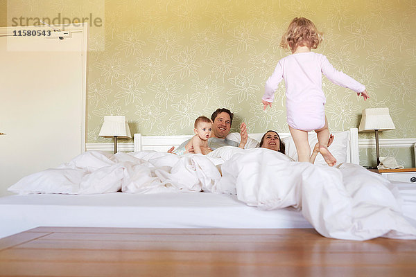 Weibliches Kleinkind betritt mit Eltern und kleiner Schwester das Bett