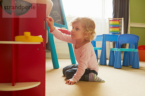 Weibliches Kleinkind spielt auf dem Boden des Spielzimmers