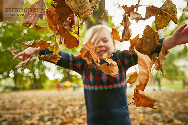 Mädchen werfen im Herbstlaub