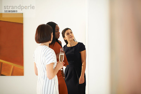 Drei Frauen betrachten Ölgemälde bei der Eröffnung einer Kunstgalerie