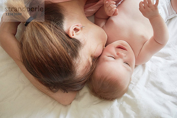 Draufsicht einer Frau auf dem Bett  die ihren kleinen Sohn auf die Wange küsst