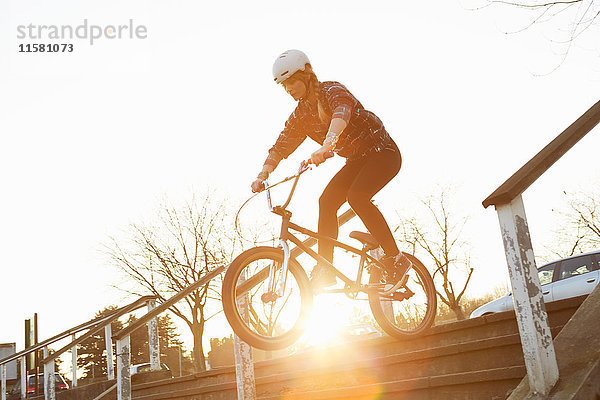 BMX-Fahrerin auf der sonnigen Treppe