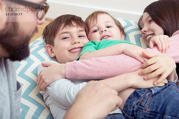 Vater und drei lächelnde Kinder auf Sitzsackstuhl liegend