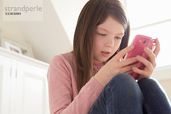 Mädchen sitzt und schaut auf Smartphone