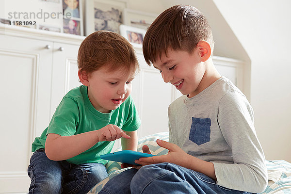 Männliches Kleinkind und Bruder schauen sich digitales Tablet an