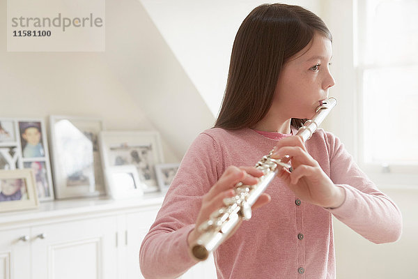 Mädchen übt Flöte im Wohnzimmer