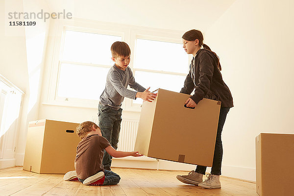 Mädchen und zwei Brüder heben Karton in neues Zuhause