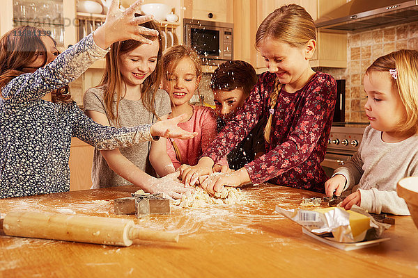 Jungen und Mädchen albern beim Backen am Küchentisch herum