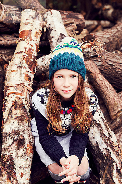 Porträt eines jungen Mädchens  das auf einem Holzstapel sitzt