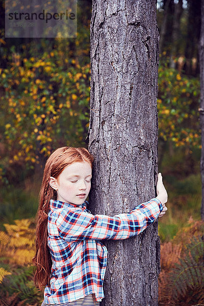 Junges Mädchen  das einen Baum umarmt