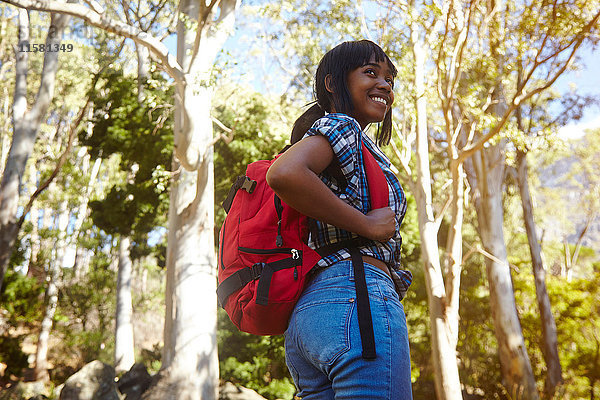 Junge Frau wandert durch den Wald  schaut über die Schulter  lächelt  Kapstadt  Südafrika