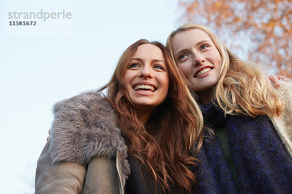 Zwei Freundinnen  die im Freien spazieren gehen  lächelnd