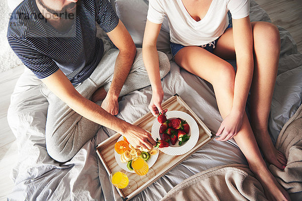 Ehepaar entspannt sich im Bett  isst Erdbeeren  erhöhte Ansicht