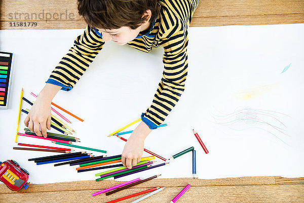 Draufsicht eines auf dem Boden liegenden Jungen Zeichnung auf langem Papier