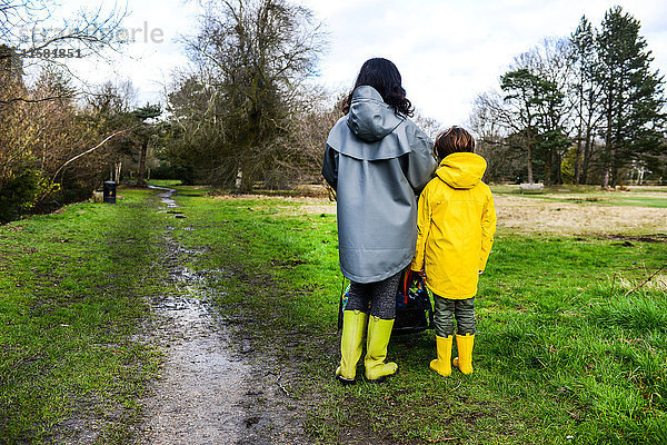 Rückansicht einer Frau mit Sohn in gelbem Anorak im Park stehend