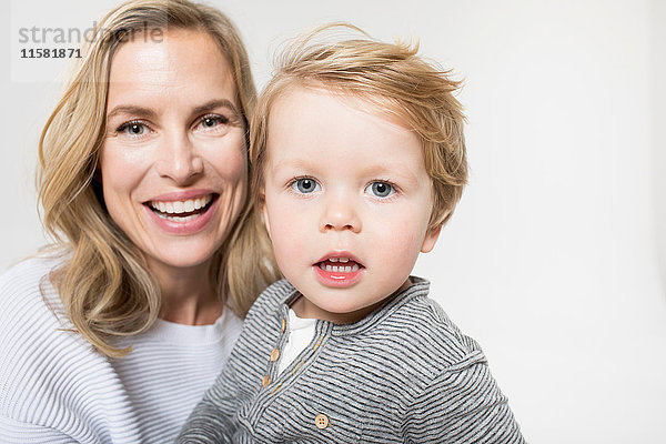 Porträt von Mutter und Sohn vor weißem Hintergrund  lächelnd