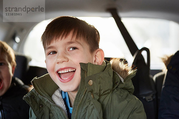 Lachender Junge auf dem Rücksitz eines Autos