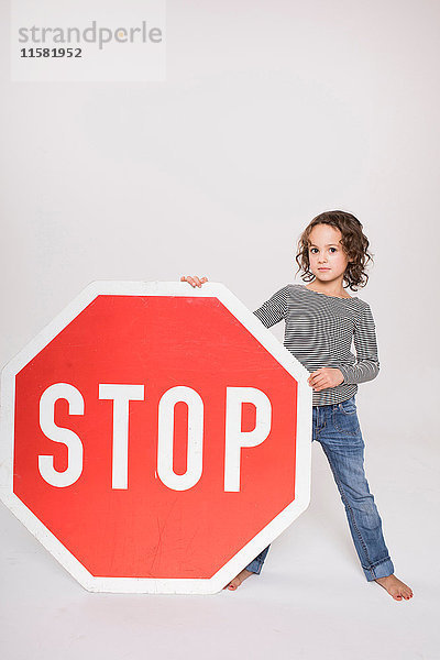 Porträt eines jungen Mädchens  das ein riesiges Stoppschild hält