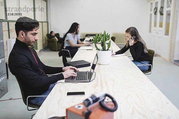 Die Unternehmer mit Laptops und Smartphone am Schreibtisch im Kreativbüro