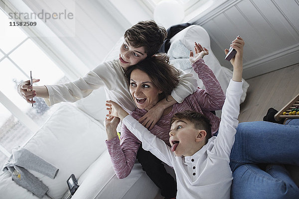 Fröhliche Mutter und Söhne nehmen Selfie im Wohnzimmer mit nach Hause.