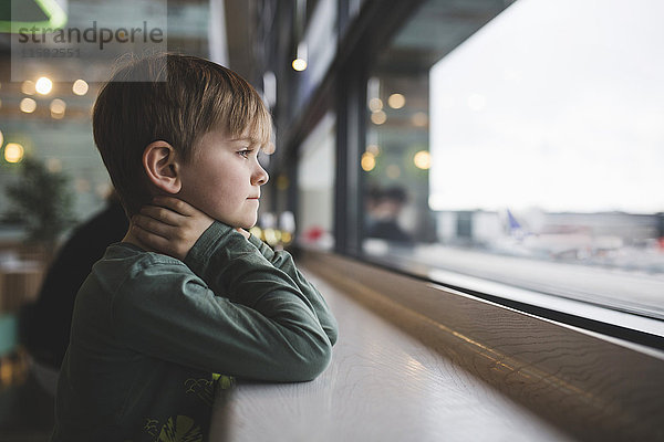 Nachdenklicher Junge lehnt sich an den Tisch am Fenster des Restaurants.