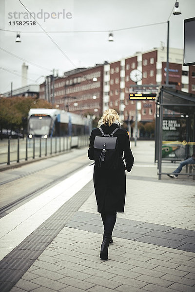 Durchgehende Rückansicht der Geschäftsfrau auf der Straßenbahnhaltestelle in der Stadt
