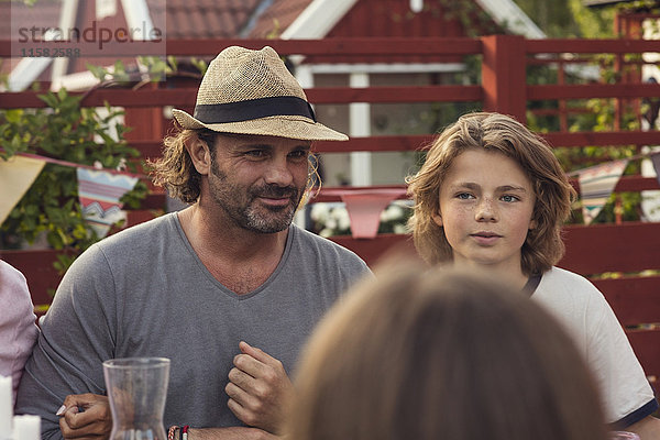 Mann sitzend mit Sohn im Garten während der Gartenparty