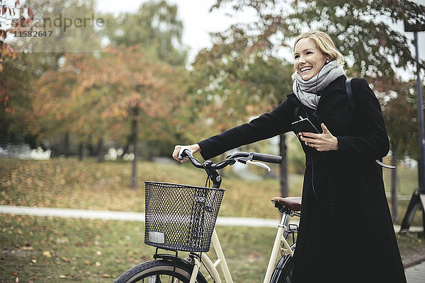Lächelnde Geschäftsfrau beim Wandern mit dem Fahrrad im Herbst