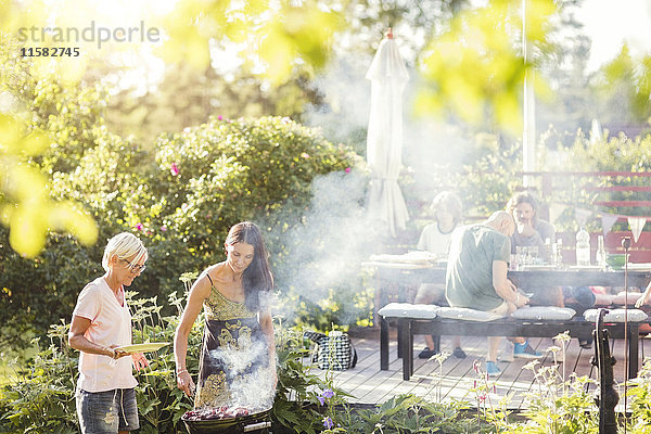 Reife Frauen beim Grillen im Garten an sonnigen Tagen