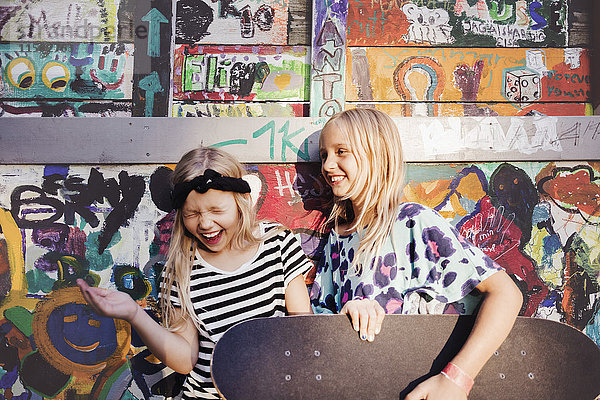 Fröhliche Freunde mit Skateboards  die sich an der bunten Wand erfreuen.