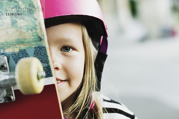 Portrait des lächelnden Mädchens mit Skateboard im Park