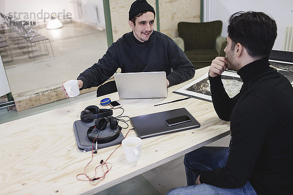 Zwei Männer diskutieren am Schreibtisch im Kreativbüro