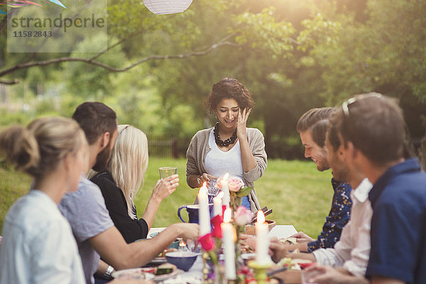 Lächelnde Frau mit Freunden bei Tisch in der Gartenparty