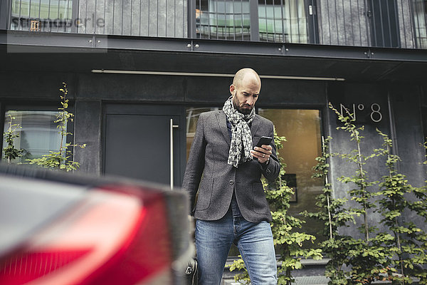 Mittlerer erwachsener Geschäftsmann mit Handy gegen Bauen