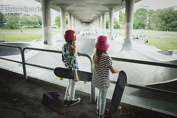 Rückansicht von Freunden  die den Skateboardpark im Stehen am Geländer betrachten.
