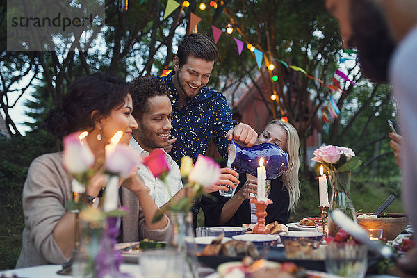 Mann  der seinen Freunden auf der Gartenparty einen Drink serviert.