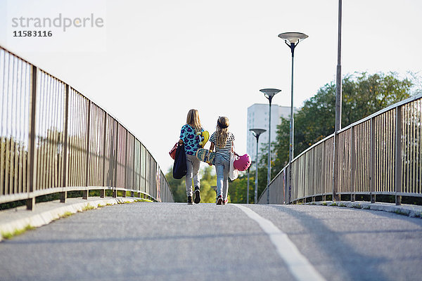 Volle Länge der Mädchen  die auf der Brücke gegen den klaren Himmel gehen.