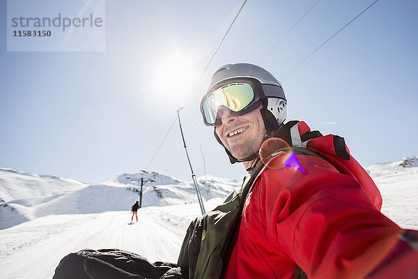 Lächelnder Mann in Skibekleidung auf schneebedecktem Feld gegen klaren Himmel