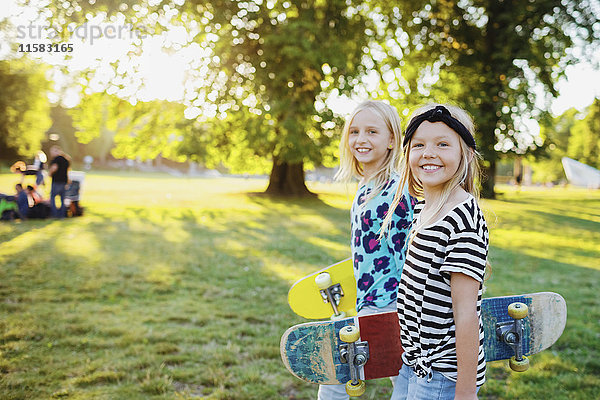 Porträt von lächelnden Freunden mit Skateboards im öffentlichen Park