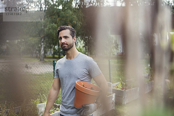 Mittlerer erwachsener Mann mit Blumentopf bei der Arbeit im Stadtgarten