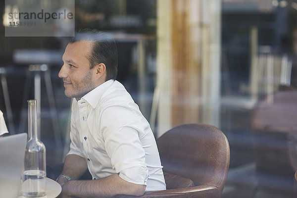 Seitenansicht des Geschäftsmannes im Restaurant vom Fenster aus gesehen