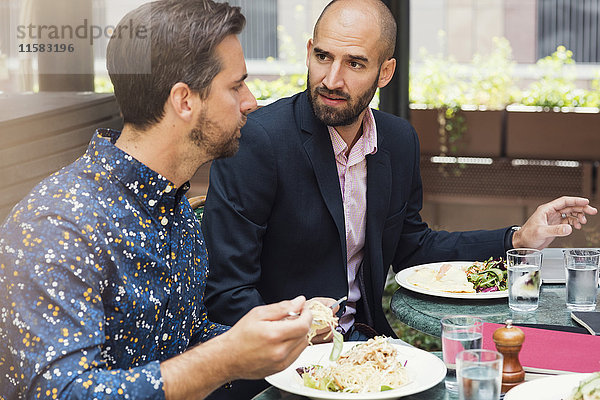 Mittlere erwachsene Geschäftsleute diskutieren beim Mittagessen im Bürohof